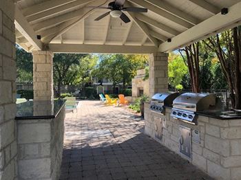 a patio with a barbecue grill and a ceiling fan